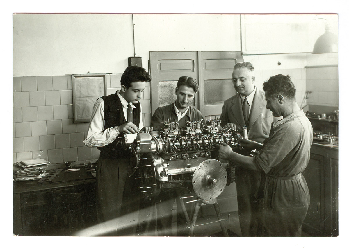 Dino Ferrari bei der ARbeit an einem V12. Mit dabei: zwei Mechaniker und sein Vater Enzo Ferrari.