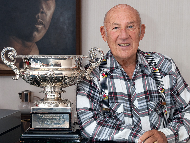 Stirling Moss posiert neben einem Pokal