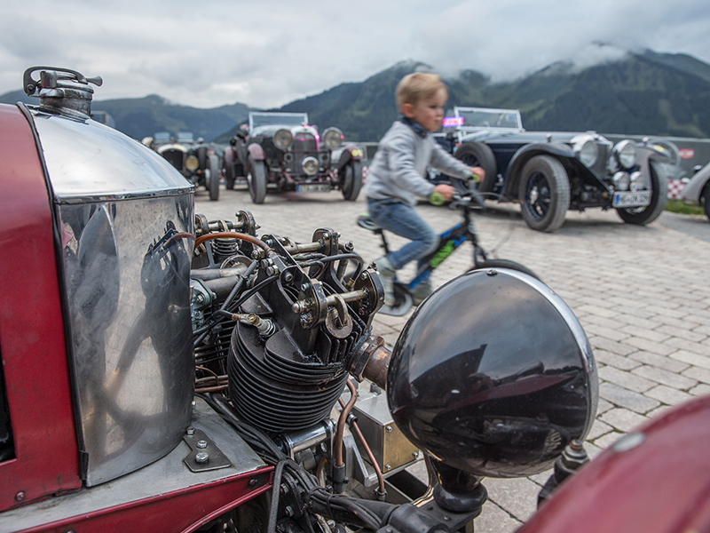 Kleiner Junge radelt auf der Saalbach-Classic an Oldtimern vorbei.